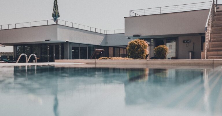 Contemporary building with reflective swimming pool on a sunny day, showcasing modern design.