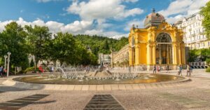 Beautiful view of the Singing Fountain and Spa Colonnade in Mariánské Lázně, surrounded by lush greenery.
