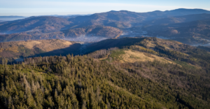 Stunning aerial photography capturing a lush, sprawling mountainous landscape under a clear blue sky.