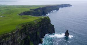 Stunning aerial view of the Cliffs of Moher, County Clare, Ireland with lush green landscapes and ocean waves.