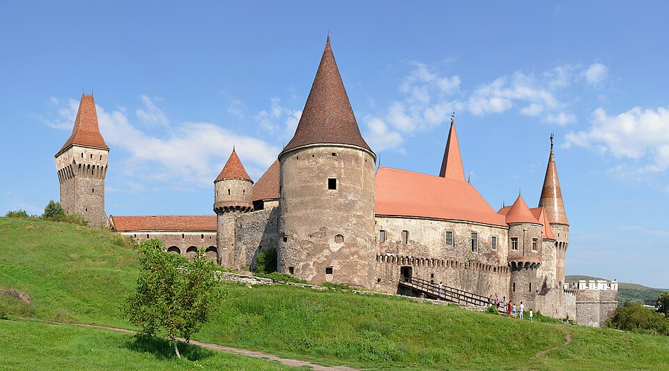 Hrad Corvín v Hunedoaře s kuželovými červenými střechami a mohutnou válcovou věží