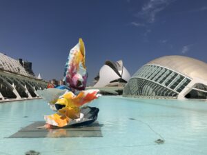 Colourful sculpture in a shallow pool at the City of Arts and Sciences in Valencia, with the Palau de les Arts and the glass dome of L'Hemisferic behind it