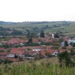 Panorama české vesnice Svatá Helena v rumunském Banátu s červenými střechami a poli v kopcích