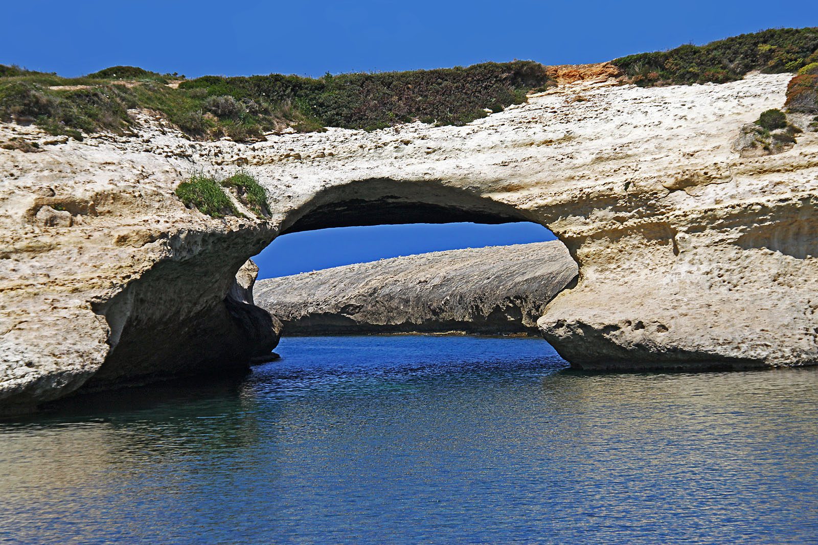 Přírodní skalní oblouk S Archittu na západním pobřeží Sardinie
