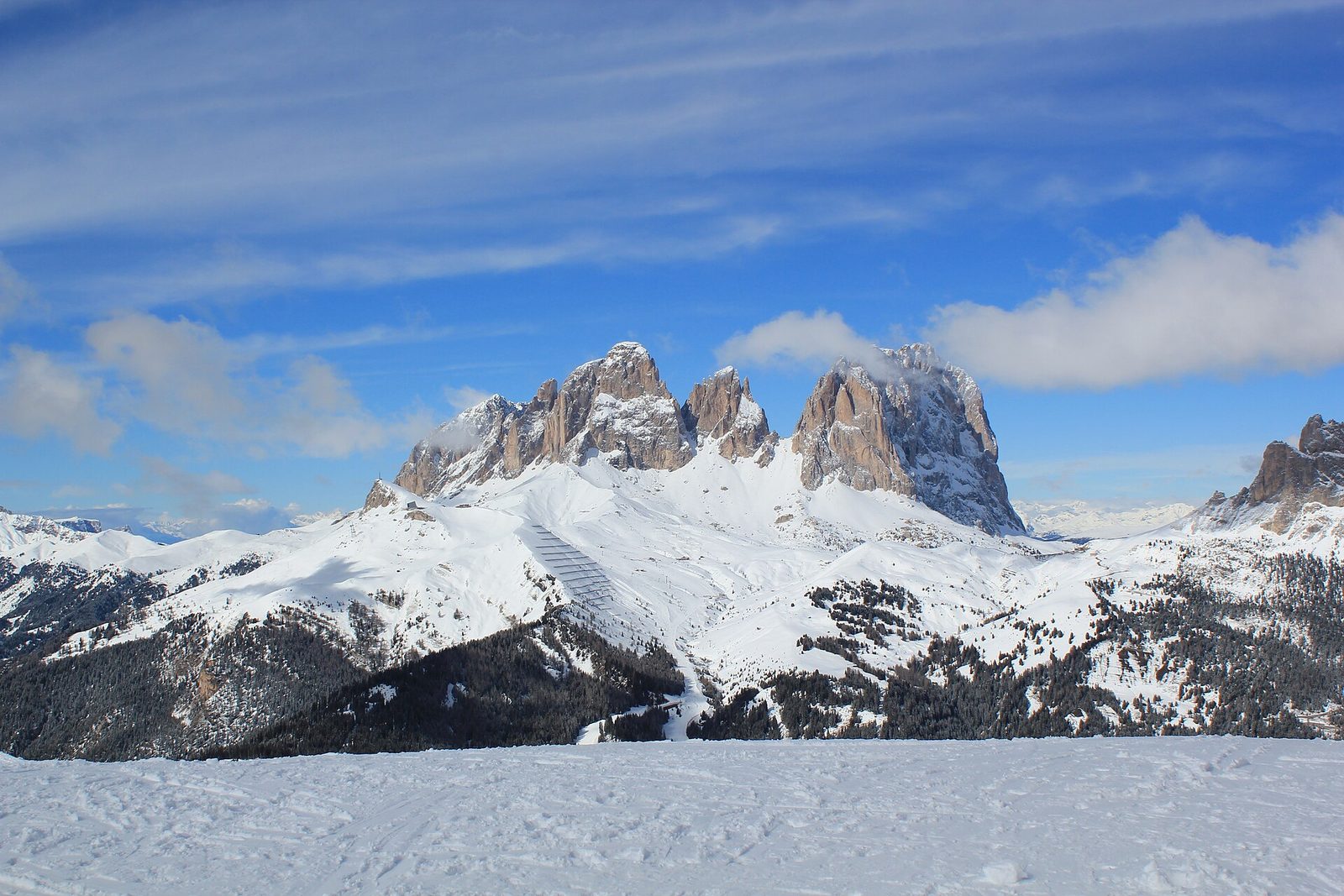 Snow-covered piste below the Sassolungo massif in the Italian Dolomites