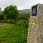 Značka s mušlí a šipkou ukazující cestu na Camino de Santiago