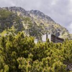 Horský hotel pod skalnatým svahem obrostlým kosodřevinou