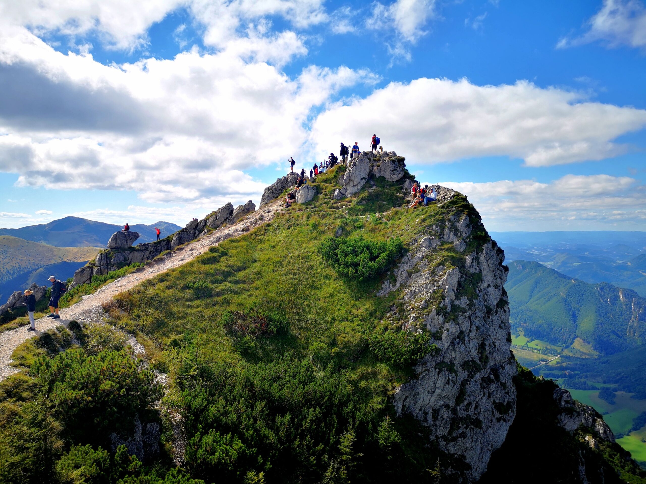 A group of walkers on a rocky summit in the Malá Fatra looking down into the valley