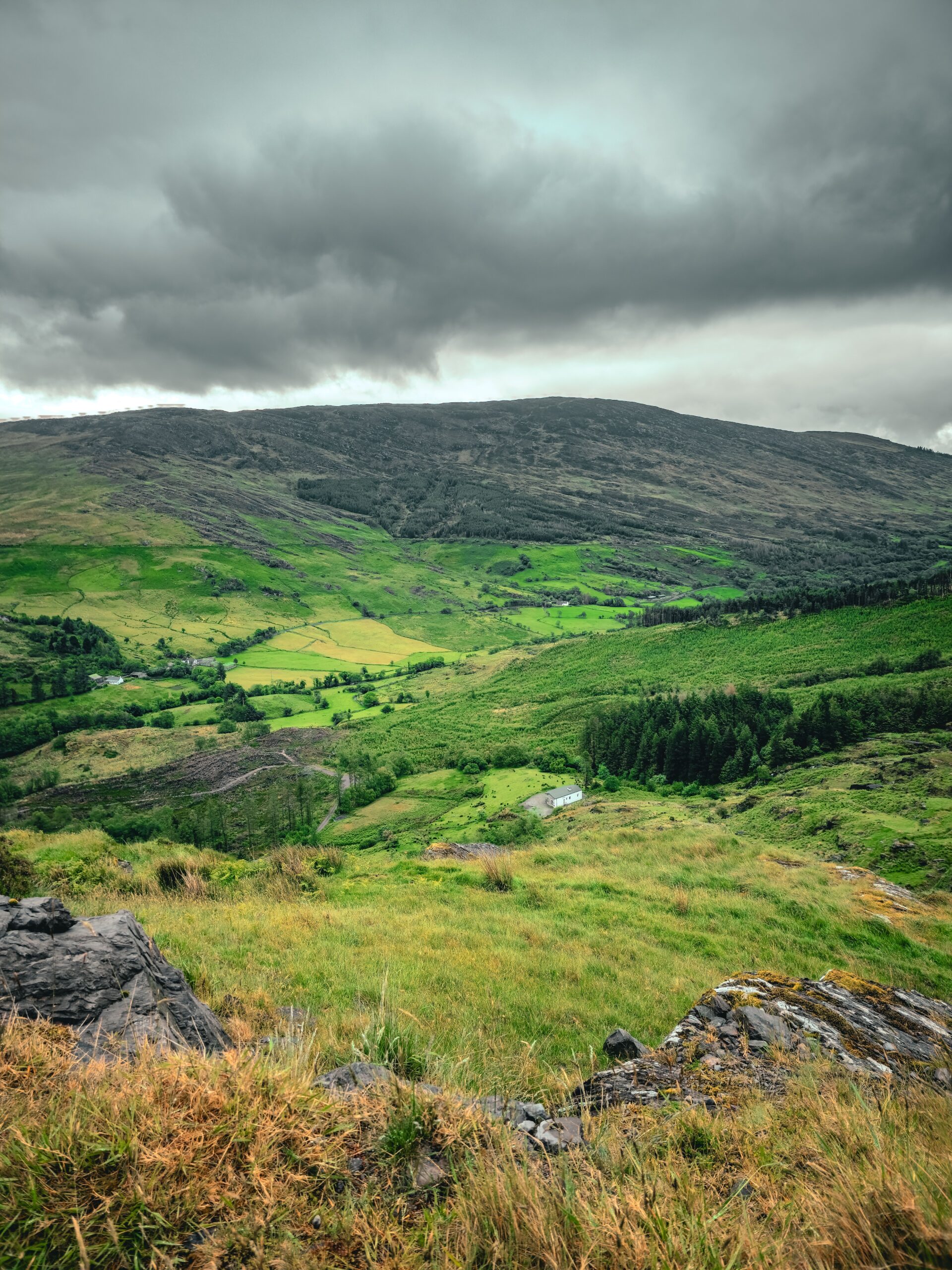 Green Irish hills and a valley beneath a dramatic sky