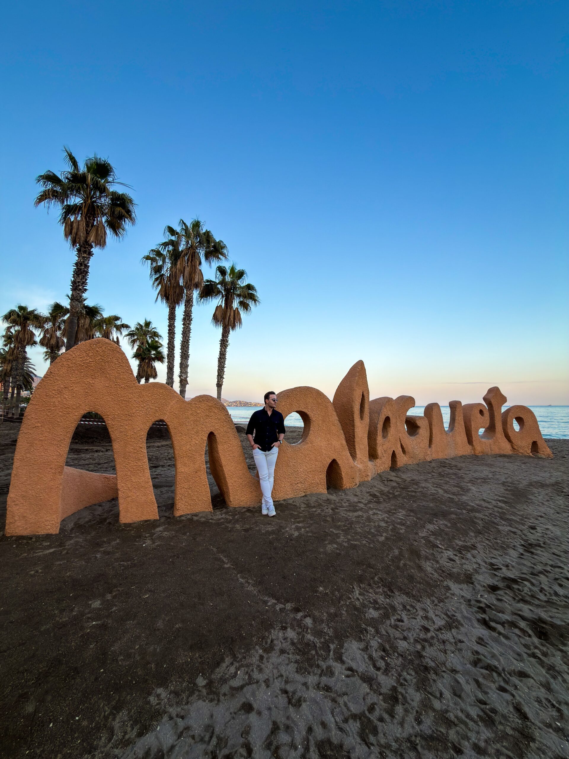 Abendstimmung am Stadtstrand Malagueta in Málaga mit Palmen und Sandskulpturen