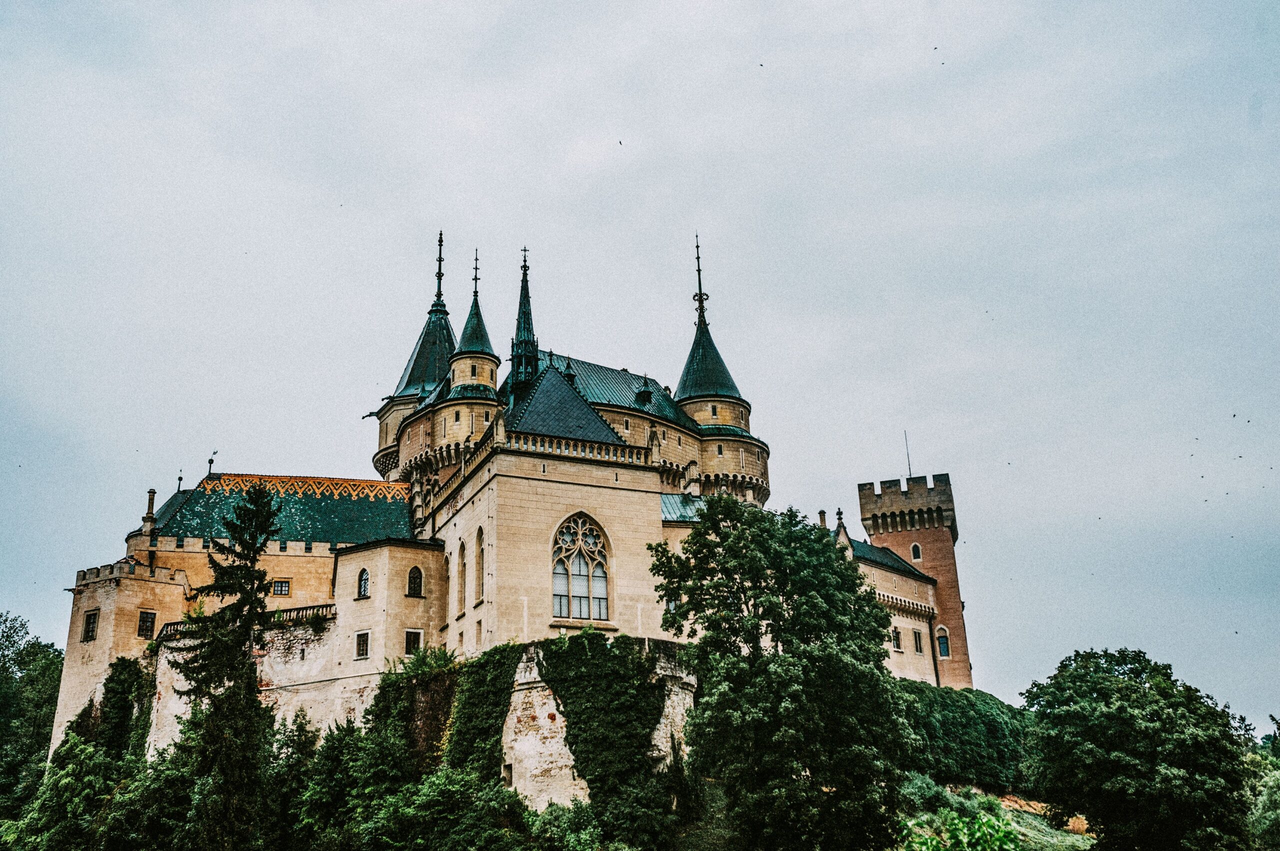 Towers and gables of Bojnice Castle rising above the treetops