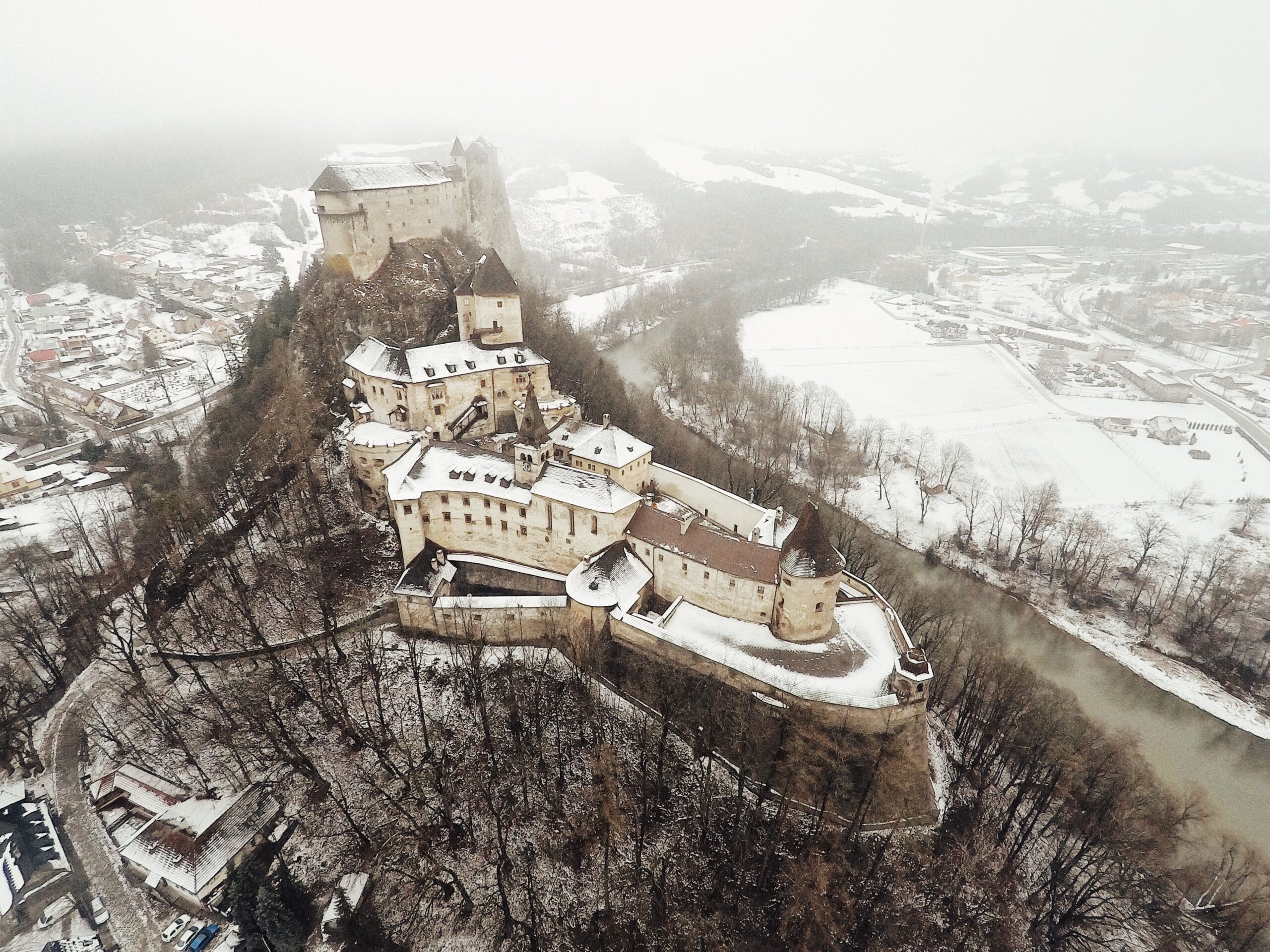 Orava Castle on its rock above the river in a snowy landscape