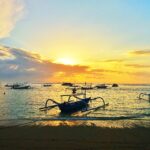 Ráno na pláži Sanur na Bali s tradiční lodí a klidnou hladinou