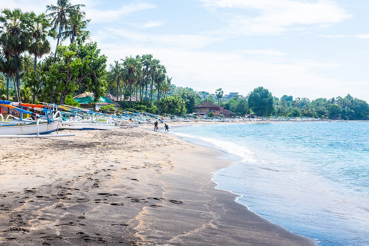 Ciemny wulkaniczny piasek i łodzie rybackie na plaży w Amedzie
