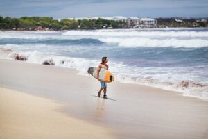 Surfař s prknem na pláži Kuta na Bali