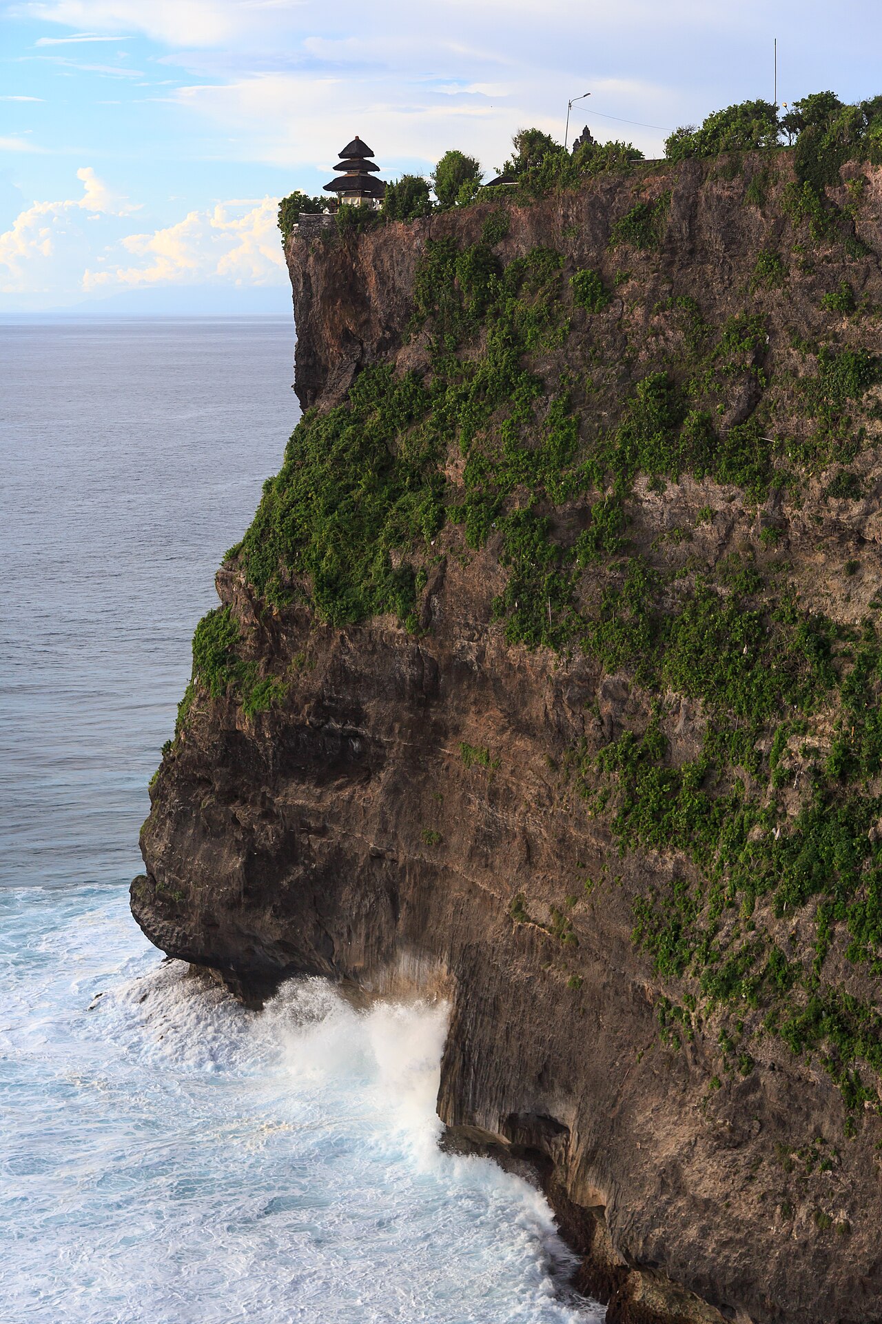 Pura Luhur Uluwatu temple on the edge of a cliff above the ocean, with waves breaking below