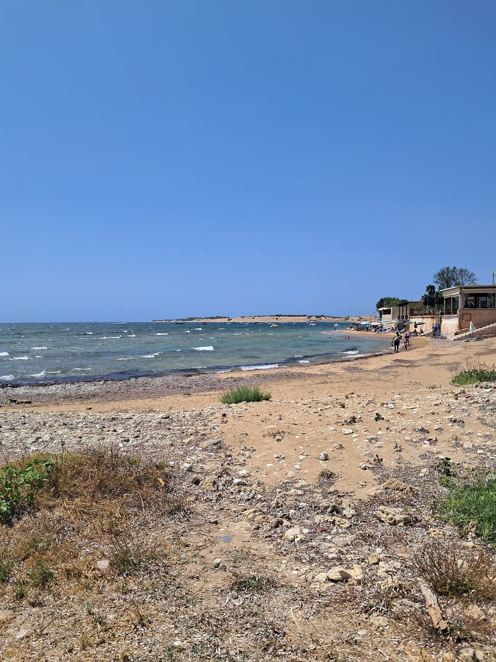 Písčitá pláž Agios Georgios South na jihu Korfu s odpoledními vlnami a beach barem v pozadí