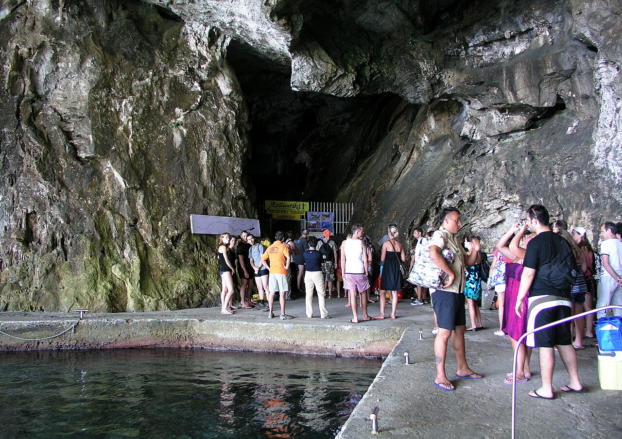 Vstup do jeskyně Grotta del Bue Marino u Cala Gonone s betonovým molem a skupinou návštěvníků čekajících na prohlídku
