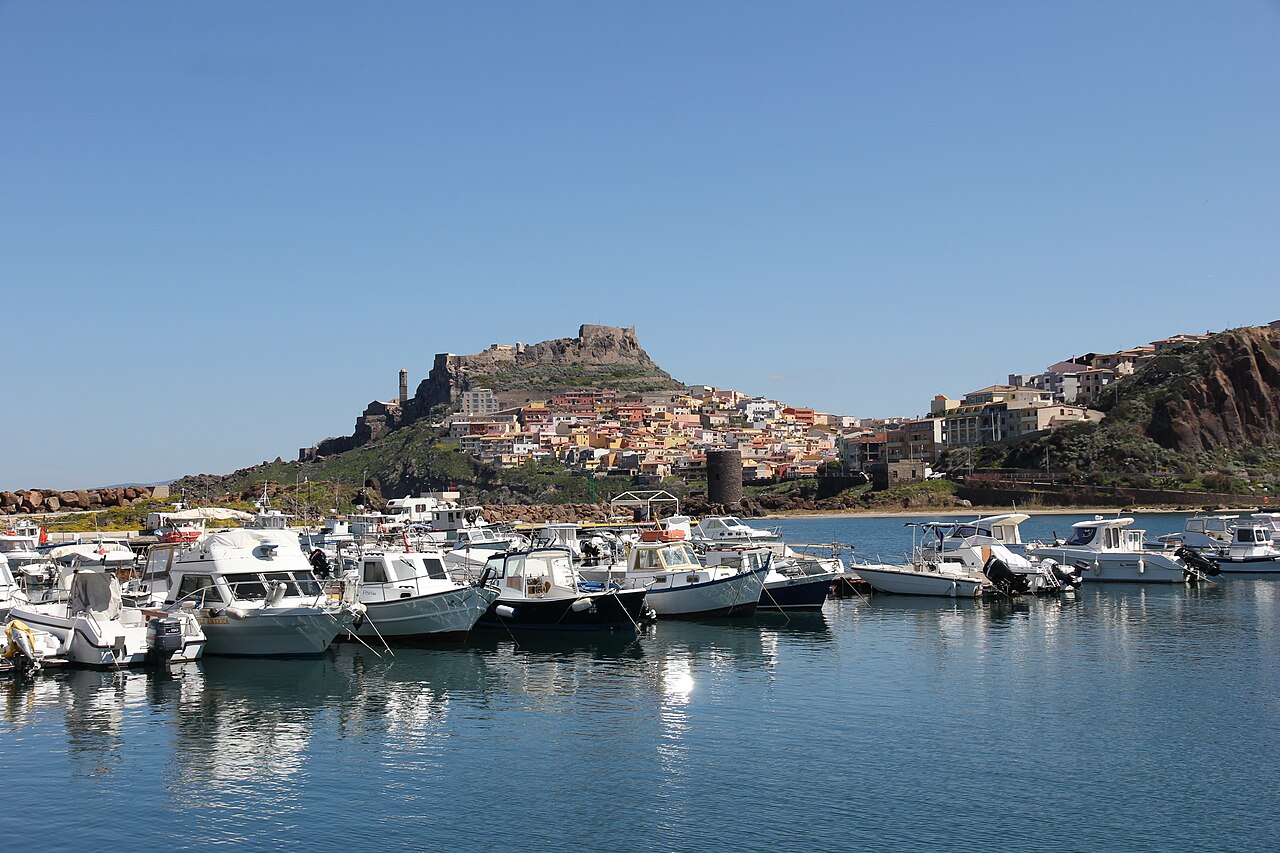 Castelsardo na skále nad přístavem s barevnými domy a hradem Castello dei Doria na vrcholu