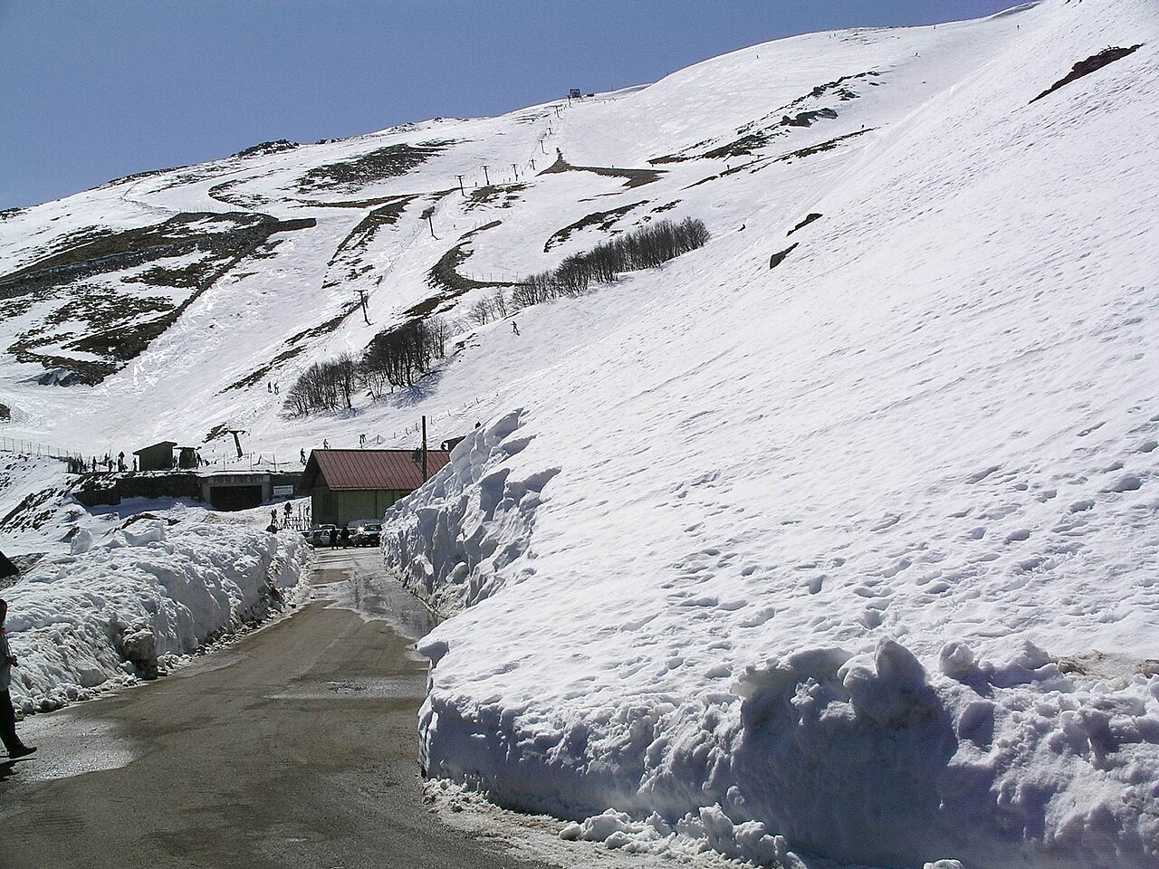 Snow-covered ski slopes at Bruncu Spina in the Gennargentu mountains, with ski lifts and high snowbanks along the road