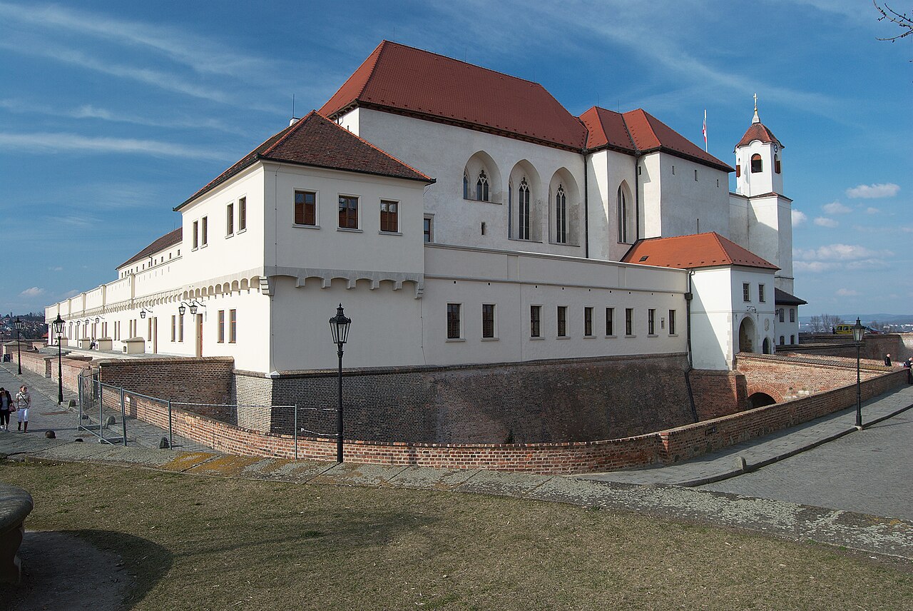Hrad Špilberk v Brně s cihlovým opevněním a bílým hradním palácem