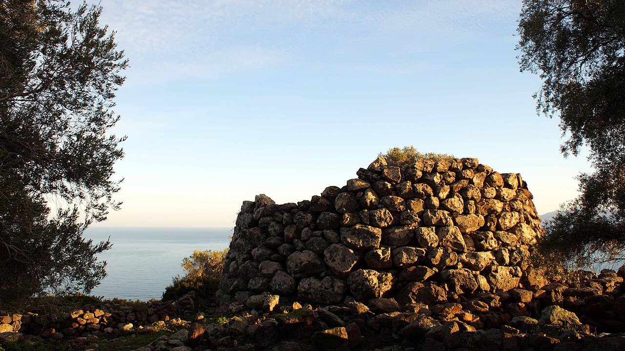 Kamenná věž Nuraghe Mannu nad Cala Gonone ve večerním světle, v pozadí moře