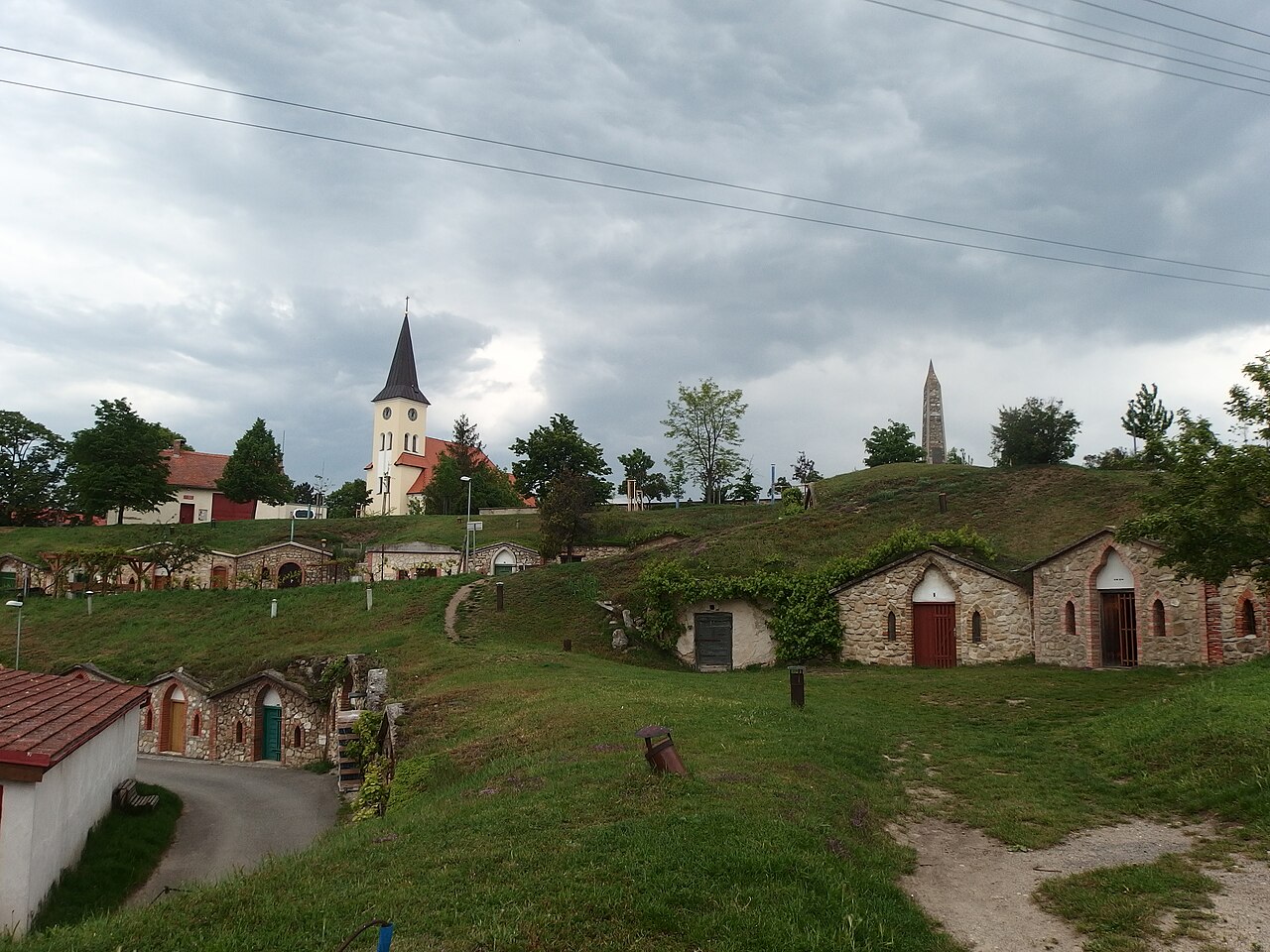 Řada vinných sklepů ve Vrbici na jižní Moravě, nad nimi kostelní věž