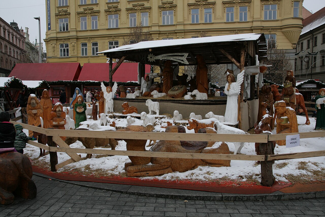 Drewniana szopka z rzeźbionymi figurami naturalnej wielkości pod śniegiem na jarmarku bożonarodzeniowym w Brnie