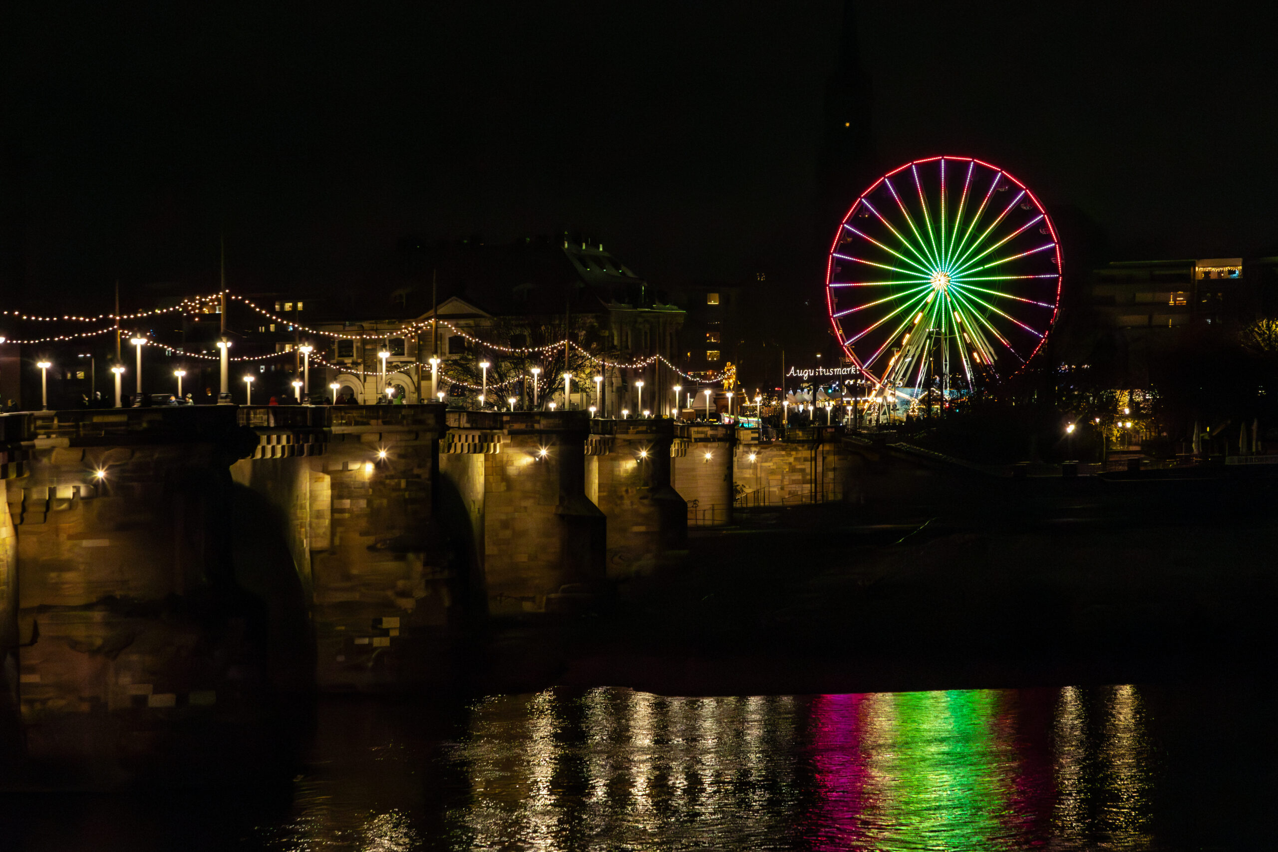 Night view across the Elbe to the Augustus Bridge and the illuminated Ferris wheel of the Augustusmarkt in Dresden's Neustadt