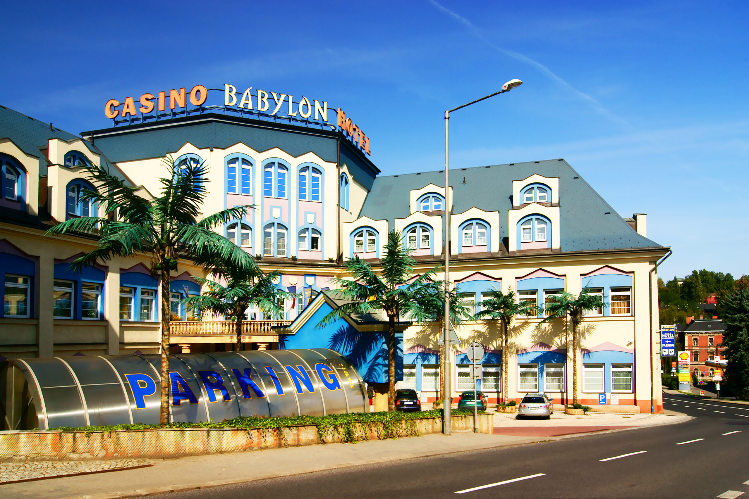Budova Centra Babylon v Liberci s nápisem Casino Babylon Hotel, palmami a vstupem do parkoviště