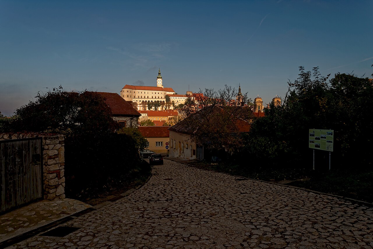 Večerní pohled z dlážděné ulice Novokopečná na zámek Mikulov osvícený zapadajícím sluncem