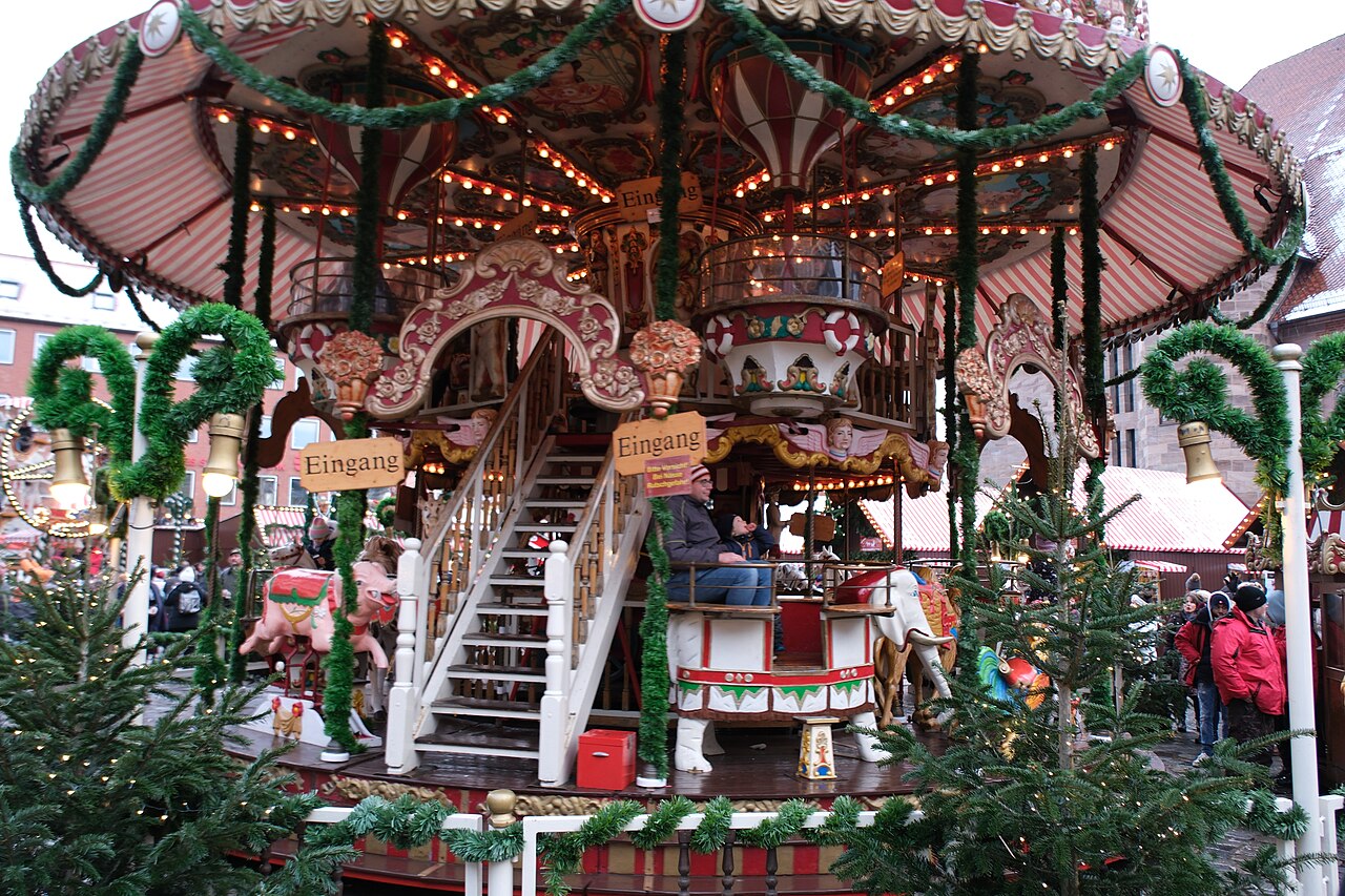 A nostalgic two-storey carousel decorated with fir branches and fairy lights at the Kinderweihnacht children's market in Nuremberg