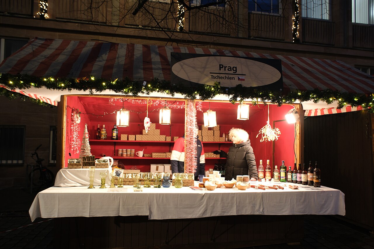 A stall signed Prag at the Sister Cities Market in Nuremberg, with glass baubles and bottles on the counter