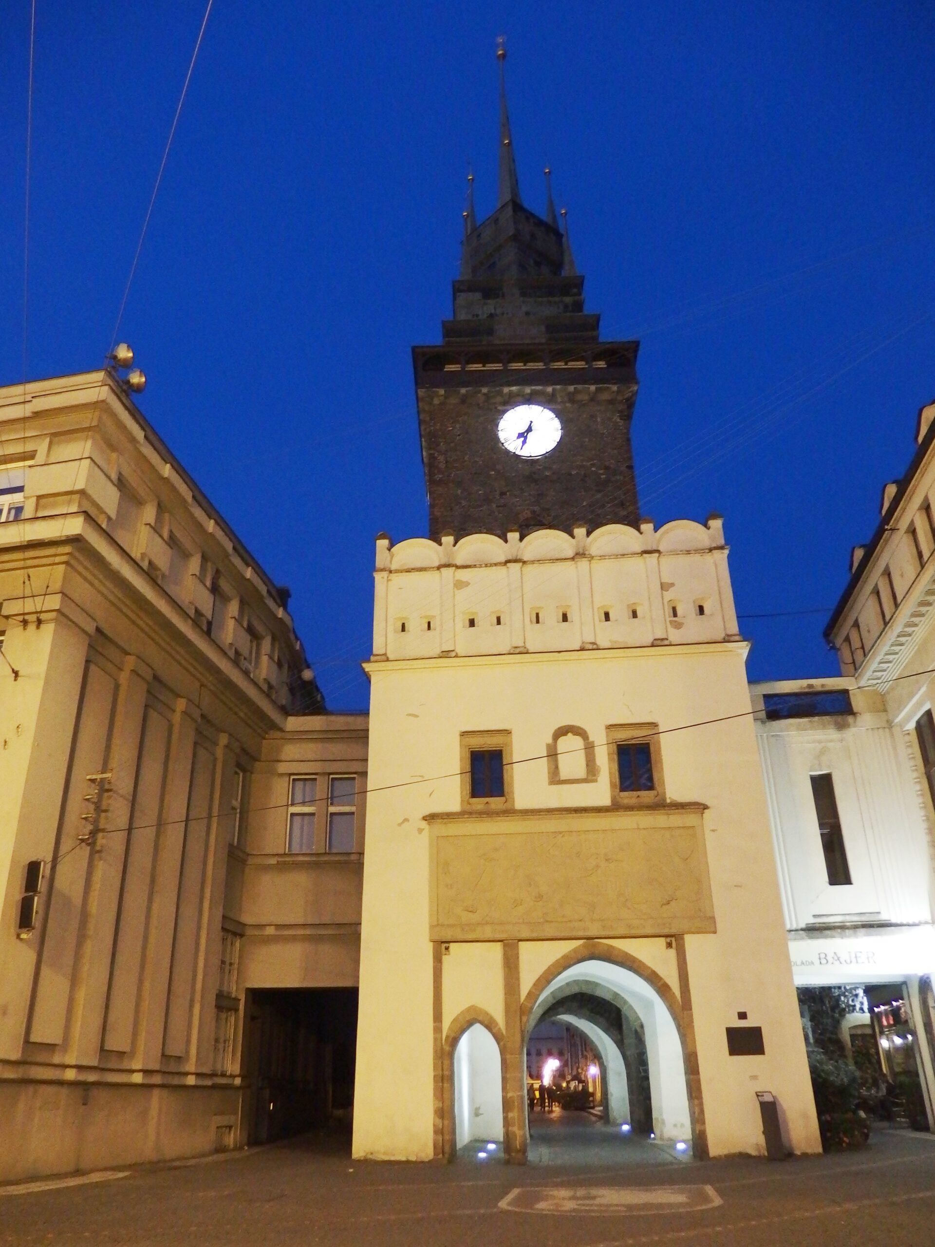Zelená brána v Pardubicích večer s osvětleným průchodem a hodinami na věži