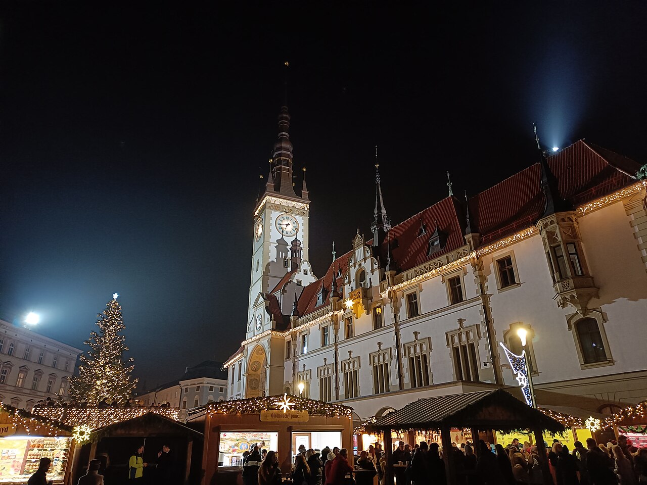 Večerní vánoční trhy na Horním náměstí v Olomouci s osvětlenou radnicí a vánočním stromem
