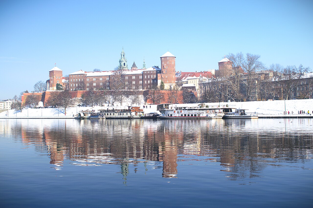 Snow-covered Wawel above the Vistula in Krakow in December, the castle and cathedral reflected in the river