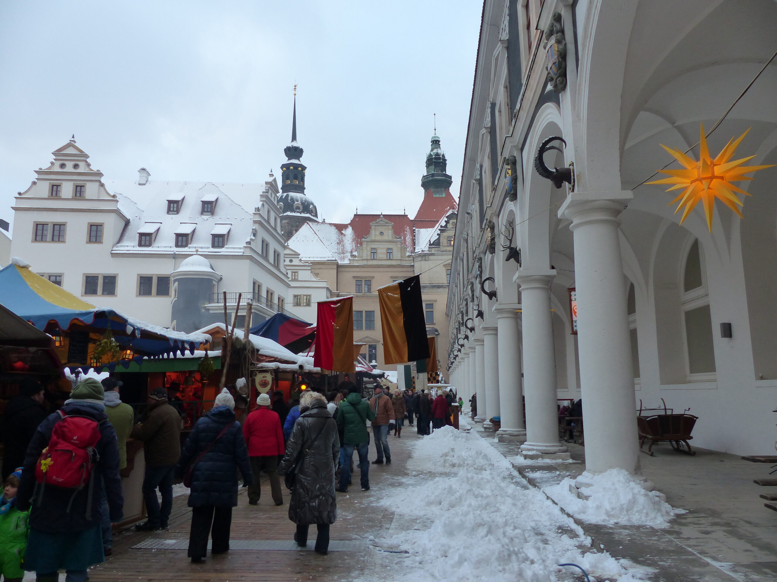 Snow-covered medieval Christmas market in the Stallhof in Dresden with the arcades and towers of the Royal Palace